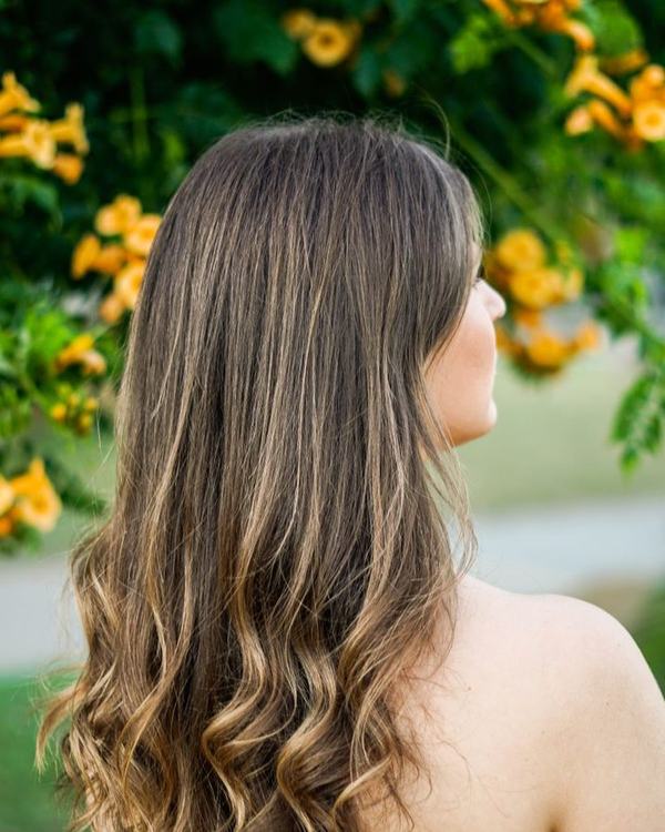 Lived-in blonde balayage on long soft waves, seen from the back
