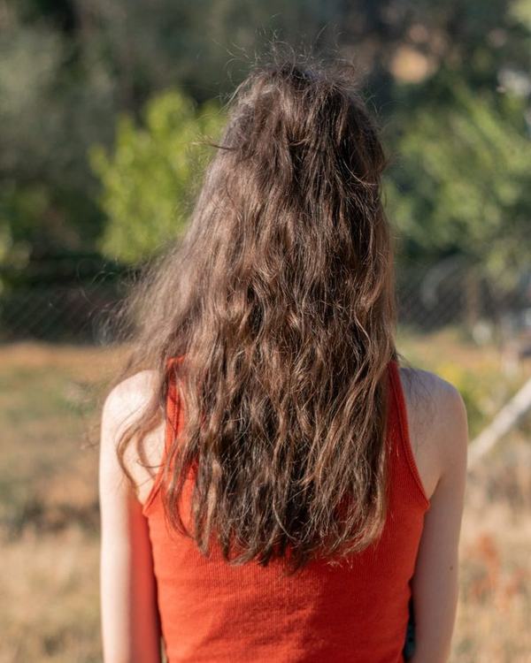Rich brunette with long loose curls, outdoors, seen from the back